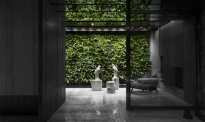 A minimalistic, industrial-style lobby with a concrete floor and a green living wall.