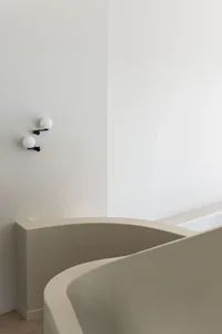 Modern, minimalist bathroom with smooth, white concrete walls and minimalist light fixtures.