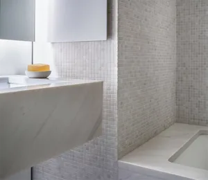 Modern, minimalist bathroom with marble tiles, floating sink, and soap dish on a countertop.
