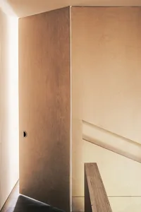 A minimalist interior with a wooden staircase.
