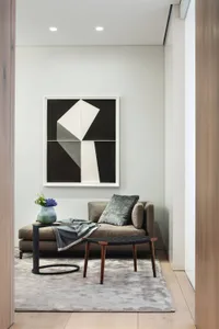 A minimalist living room with a gray sofa, geometric artwork, and modern side table.