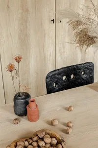 A minimalist table setting featuring wood and natural elements like dried flowers and walnuts.