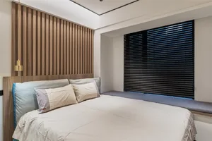 Modern bedroom with a bed featuring fabric bedding and a wooden headboard.