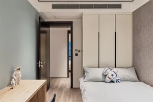 A modern bedroom featuring a wooden desk, upholstered bed with a decorative pillow, and metal accents.