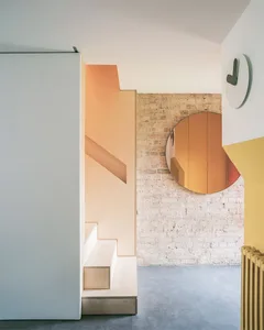A modern interior space featuring wooden stairs, brick walls, and concrete flooring.