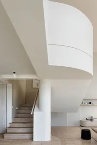 Modern interior with white walls, wooden stairs, and a minimalist design aesthetic.