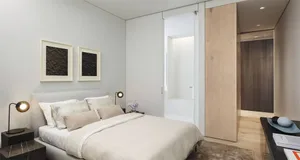 A modern minimalist bedroom with a wooden bed frame and a glass side table.