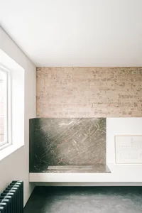 A modern industrial kitchen featuring exposed brick walls and a marble backsplash.