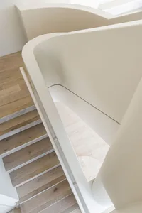 Modern architectural staircase with wooden steps and concrete walls.