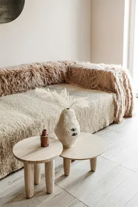 Modern living room with wooden furniture, fur blanket, and textiles.