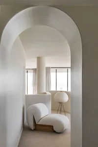 Modern, minimalist living room with white furniture and white lamp.