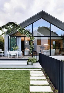 Modern minimalist house exterior with concrete structure, large glass windows, and green plant decor