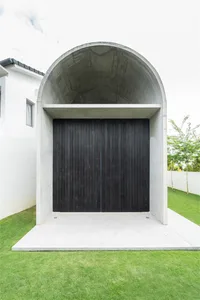 A modern minimalist entryway with a concrete tunnel and black wood doors.