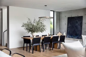 A modern dining room with a wooden table and black chairs.