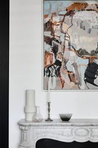 A modern abstract painting displayed above a marble console table, adorned with a candlestick holder and a bowl.