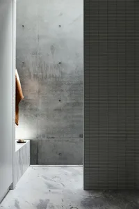 Modern industrial bathroom featuring concrete walls and marble floors.