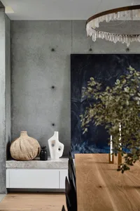 Modern minimalist interior featuring a concrete wall with abstract sculptures and a chandelier.
