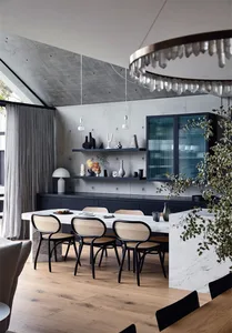 A modern dining room featuring a table, chairs, and decorative shelving against a concrete wall.