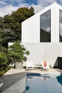 A modern home exterior features concrete and glass materials with a swimming pool.