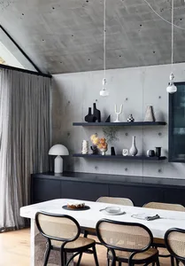 A minimalist dining room with concrete walls and white marble table.
