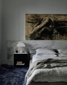 Minimalist-style bedroom featuring a grey bed, white furniture, and a black side table.