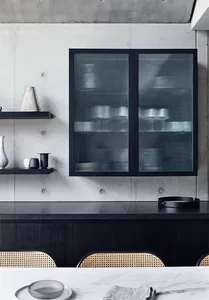 A minimalist kitchen featuring a black glass cabinet with ridged glass doors.