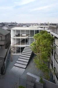 A two-story house with large glass windows and concrete stairs.