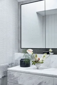 A modern minimalist bathroom with marble countertop, white tiles, and concrete wall.