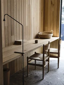 A modern study space featuring a wooden desk with a minimalist design, complemented by a woven basket and a sleek lamp.