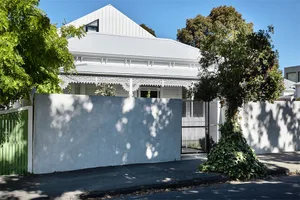 A modern, white house with a concrete wall on the street.