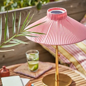 Pink paper lamp on wooden table with leaves and cocktail on glass