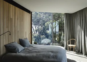 Minimalist bedroom featuring a bed with wood paneling, glass windows, and a gray fabric headboard.