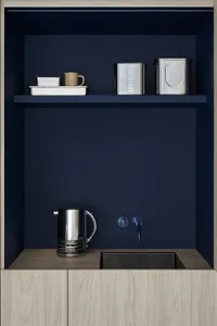 A modern kitchenette featuring metal shelves and a sink with a water dispenser.