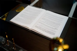 An open book displaying text on a desk with a ruler and decorative items.