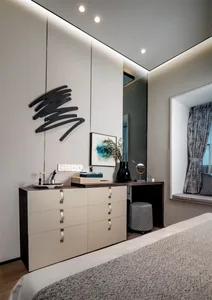 Modern minimalist bedroom with white furniture, geometric wall art, and gray curtains.