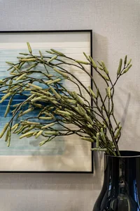 A modern living room with a metallic vase adorned with botanical decorations.