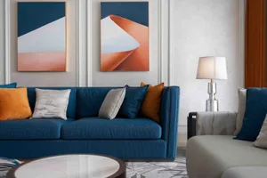 A modern living room with a blue sofa, white coffee table, and abstract art on the wall.