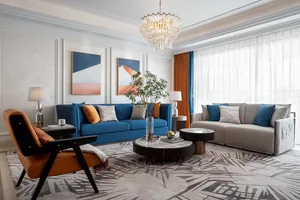 A modern living room featuring textured cloth furniture, contemporary artwork, and a crystal chandelier.