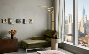 Minimalist living room with a green velvet couch, white curtains, and a cityscape view from a large window.
