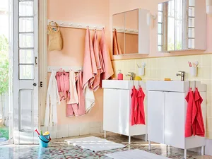 A vintage pink bathroom with modern fixtures and hanging towels.
