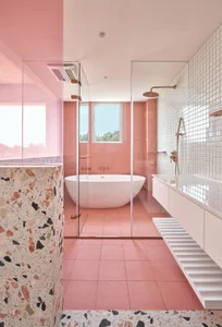 Modern minimalist bathroom with pink tiles, freestanding bathtub, and white floating vanity.