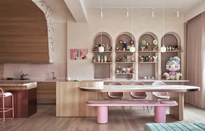 A modern kitchen with white countertops and wooden furniture, featuring a dining table, chairs, and a kitchen island with sin