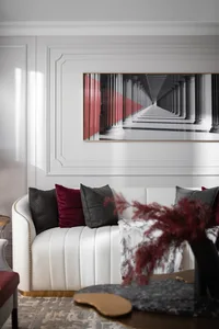 Modern living room featuring a white sofa, red accent pillows, and a red and white abstract painting on the wall.