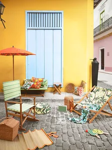 An outdoor space featuring vibrant yellow walls, wooden lounge chairs, and colorful decorative elements.