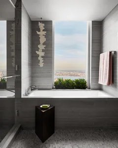 Modern bathroom with gray tiles and concrete accents, featuring a bathtub with a view.