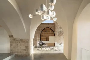 A modern interior space with architectural brick walls and concrete flooring, featuring a sleek chair and minimalistic decor.