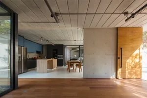 Modern residential kitchen and dining area with concrete and wooden elements