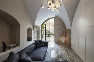 Modern living room with concrete walls, arched ceiling, and minimalist furniture.