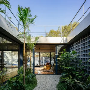 A modern residential patio featuring concrete flooring and surrounded by lush green plants.