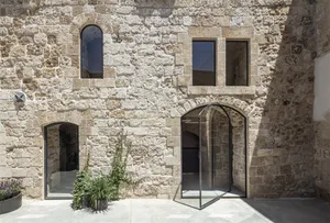 Modern residential facade made of stone with large windows and a glass door.